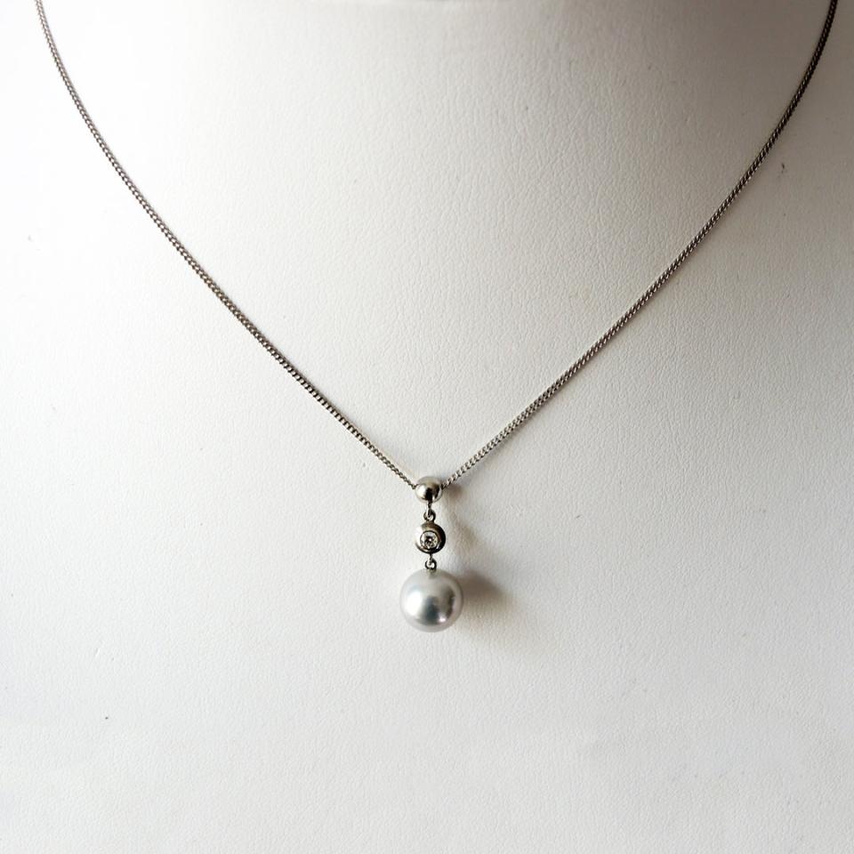 Platinum pendant with an .05 ct. bezel set diamond and a 9 mm pale blue Akoya pearl on a prop neck.