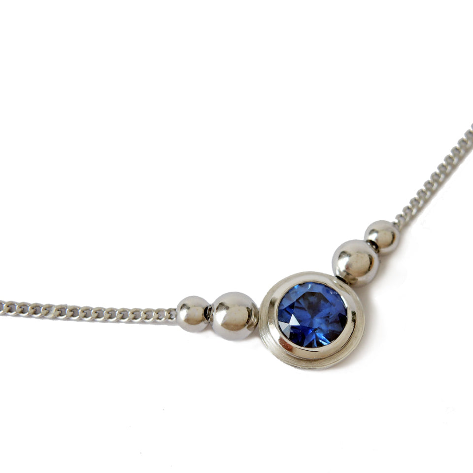 6 mm blue sapphire pendant set in platinum double bezels with 4 beads on the chain