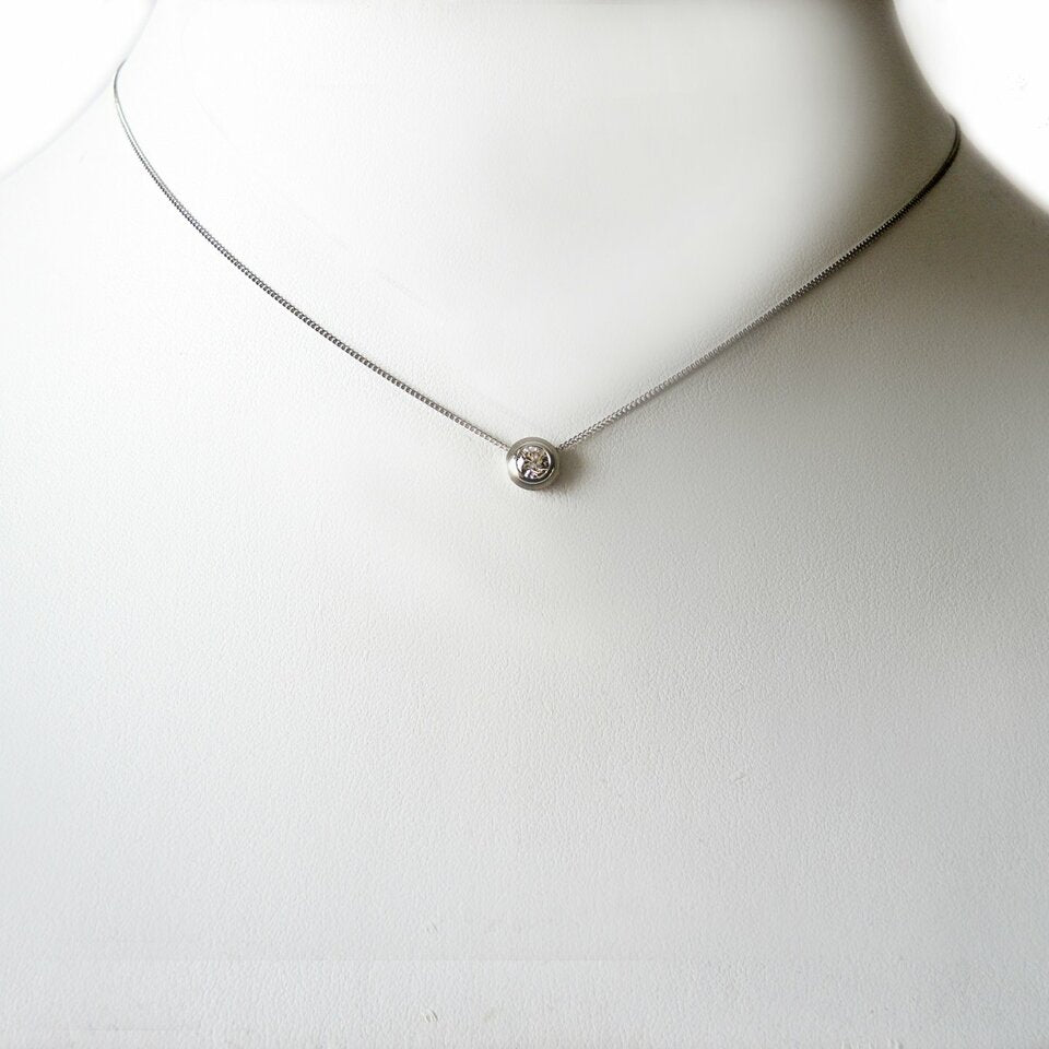 A simple solitaire .25ct. diamond pendant, in a platinum double bezel that slides on a 1mm chain.