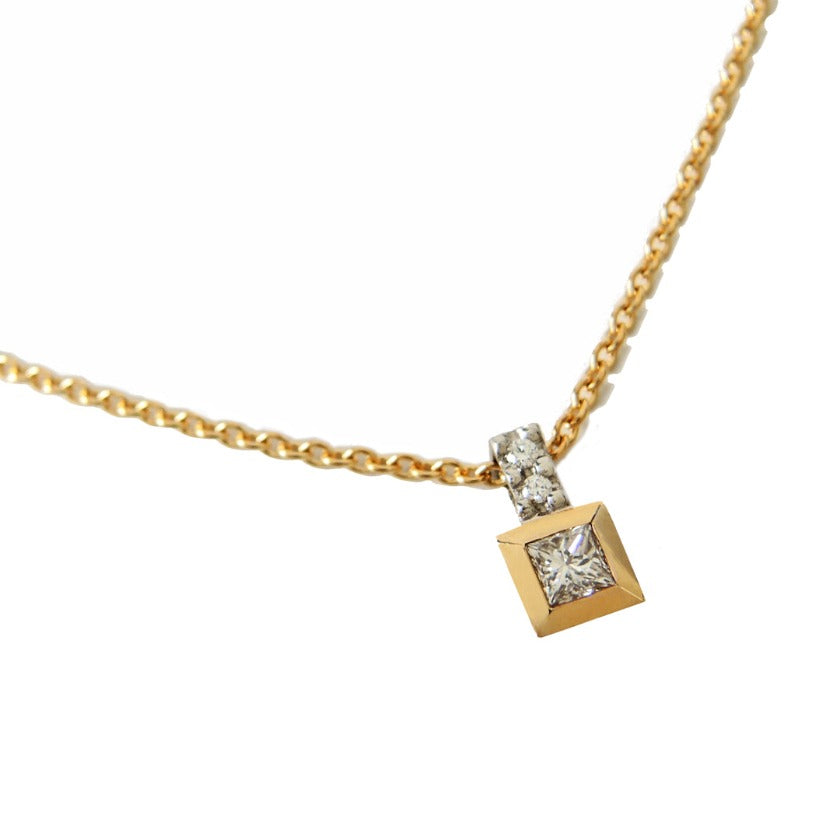 Princess cut diamond in a gold bezel with a platinum bail with two small diamonds.