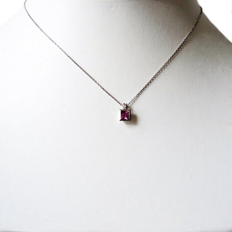 Princess cut pink sapphire set in a platinum bezel on a 1 mm chain on a prop neck