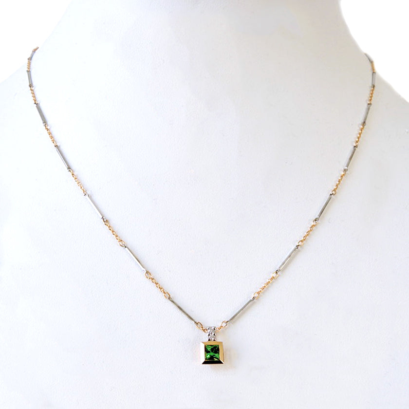 Princess cut tsavorite bezel set in 18k with a platinum bail, gold and platinum chain on a white prop neck.