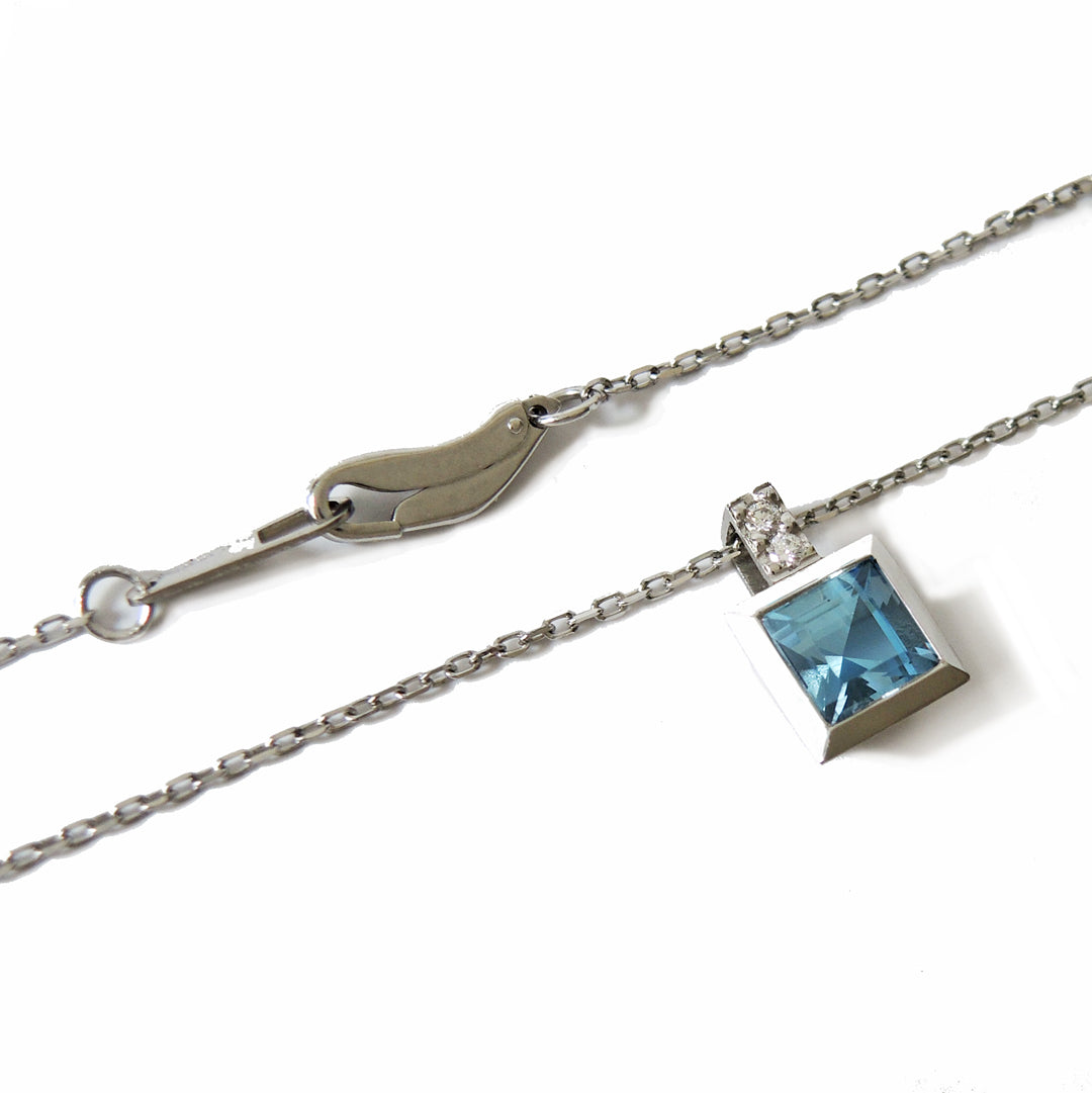 5 mm step cut aquamarine set in a platinum bezel with two small diamonds in the bail with a fine platinum chain and lobster clasp.
