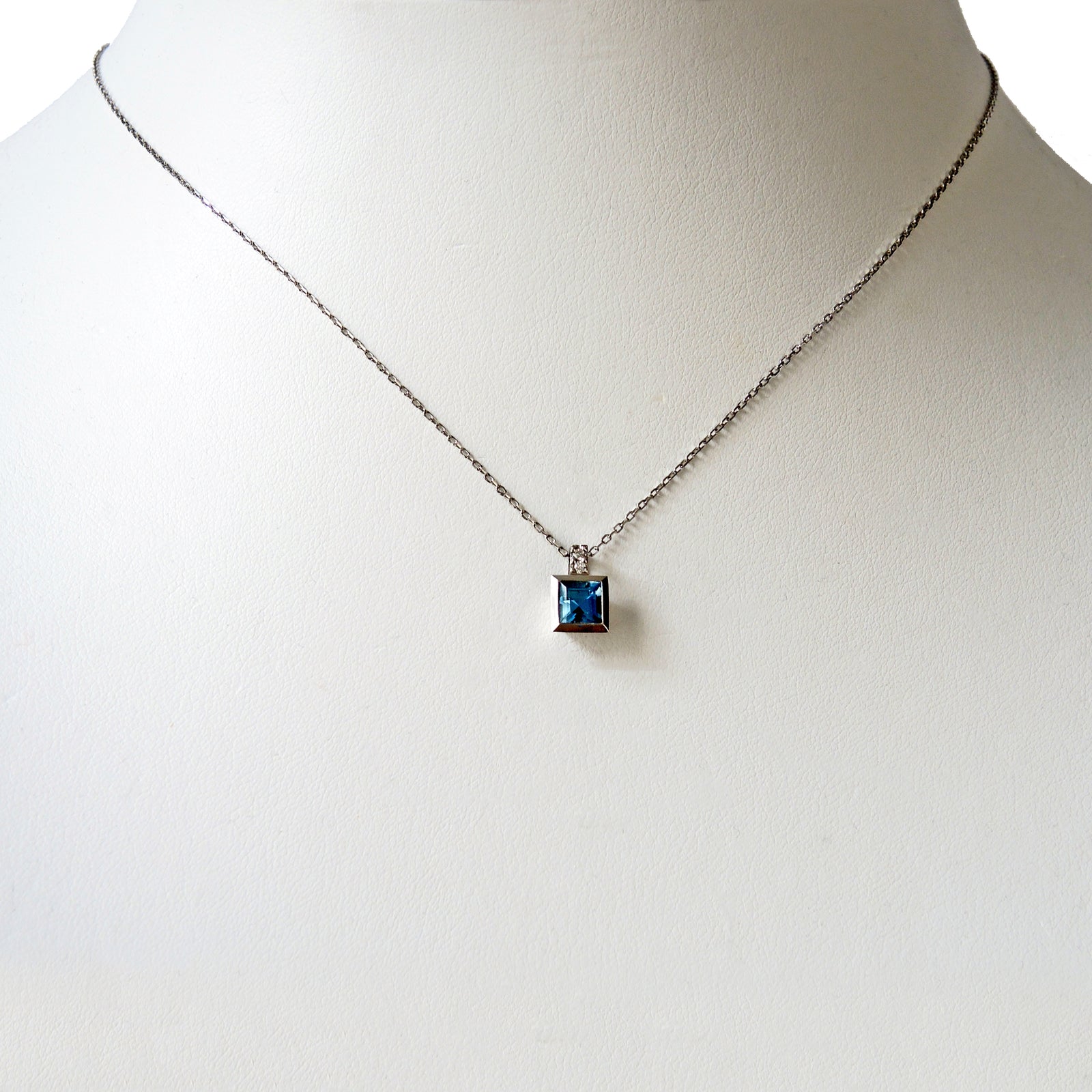 5 mm step cut aquamarine set in a platinum bezel with two small diamonds in the bail with a fine platinum chain and lobster clasp.