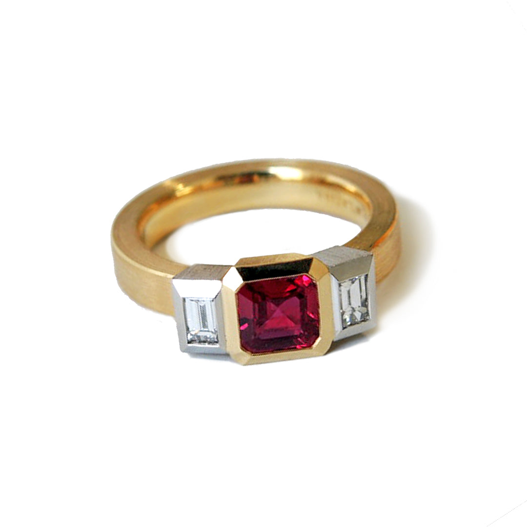 a bezel set 3 stone ruby ring in 18k and platinum with diamond baguette side stones