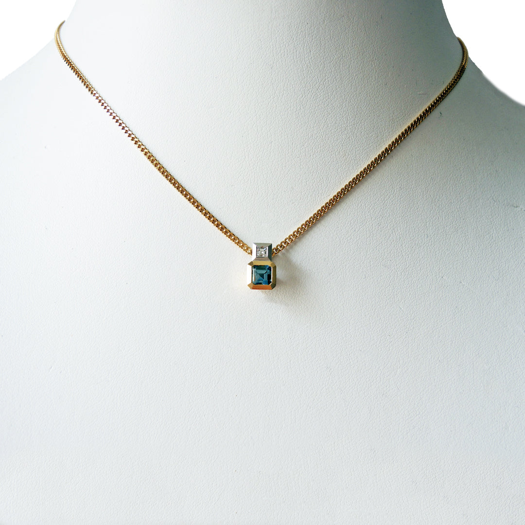 Aquamarine and diamond pendant, bezel set in 18k and platinum on an 18k gold chain on a white prop neck.
