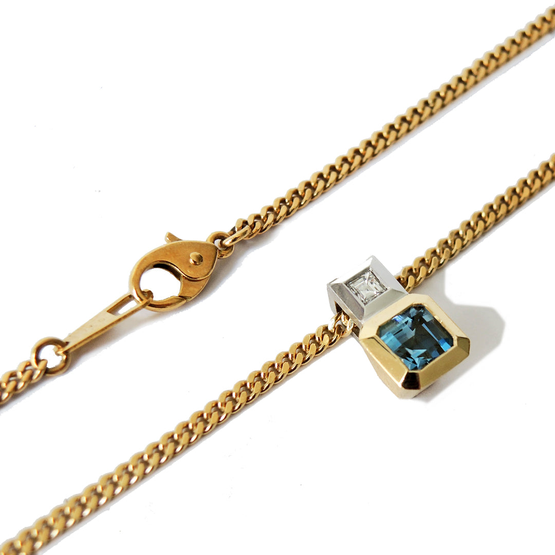 Detail of an aquamarine and diamond pendant, bezel set in 18k and platinum on an 18k gold chain showing the clasp and chain tag.