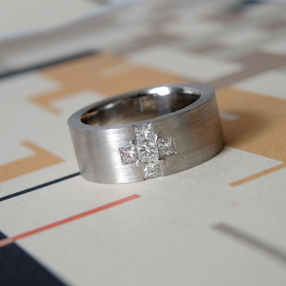 Wide 18k white gold band with flush set princess cut diamonds in a cross shape.