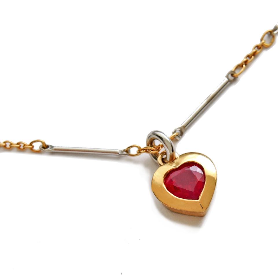 Bezel set heart shaped ruby in 18k gold on a platinum and 18k bar chain