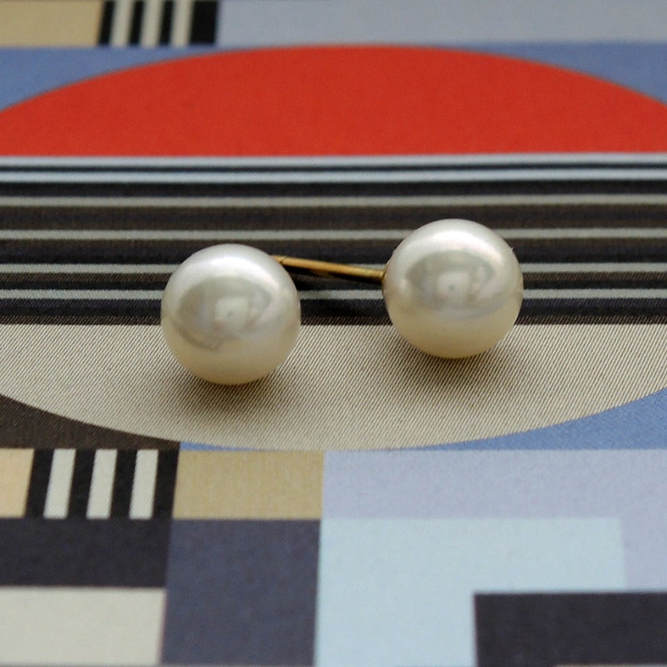 7.75 mm fine quality white Akoya pearls with 18k pearl cups on a patterned background