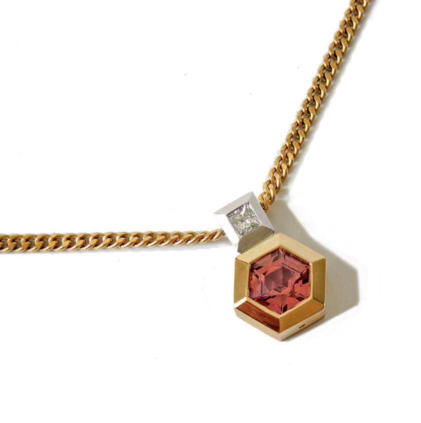 Pendant with hexagonal pink sapphire bezel set in gold and princess cut damond bail in platinum on a white backgound.