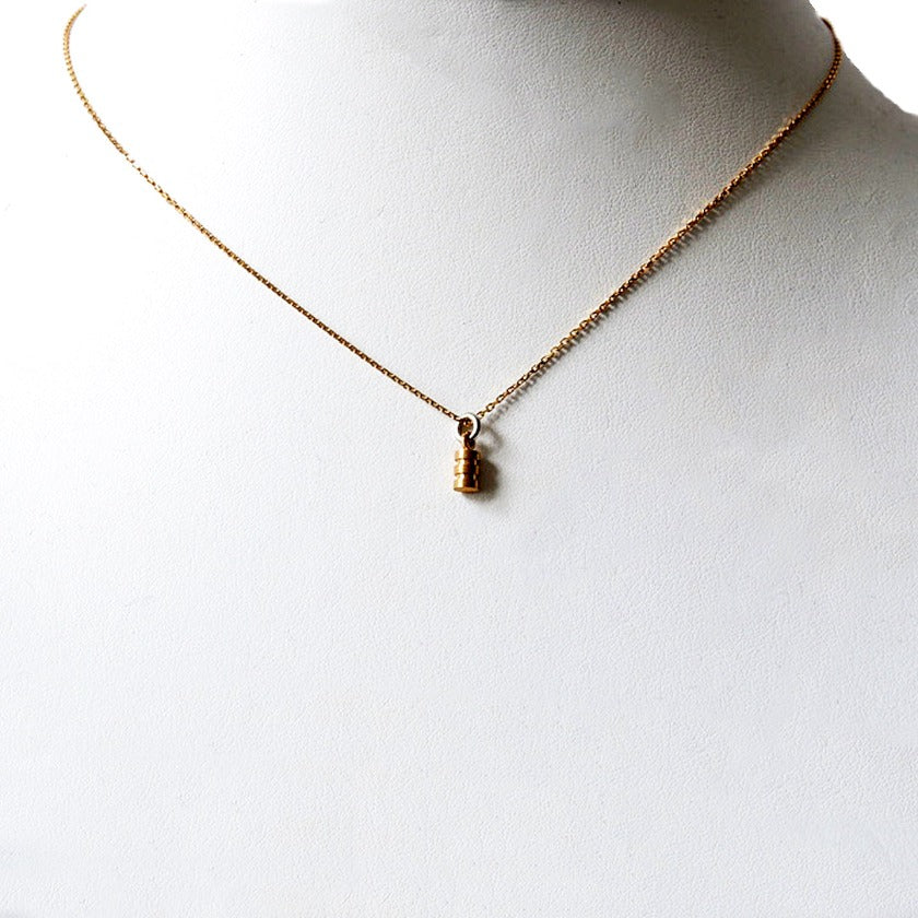 Lath Turned Mini Barrel Pendant in 18k gold on white prop neck