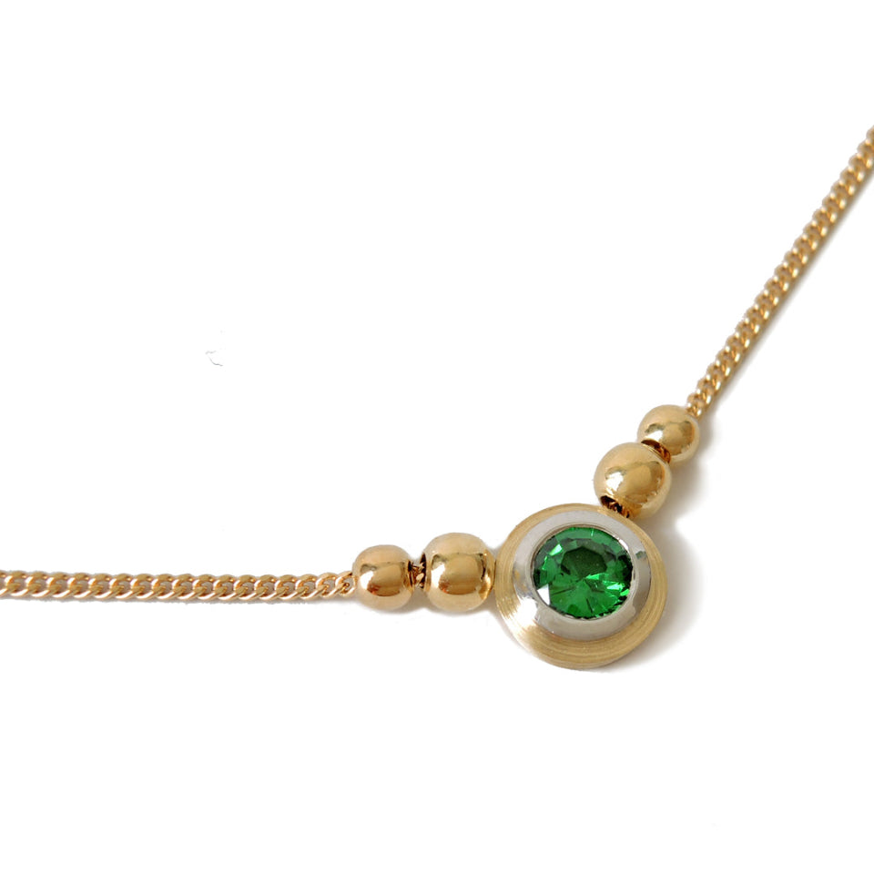 Tsavorite (green garnet) bezel set in platinum and 18k on a fine 18k chain with 4 18k beads on a white background.