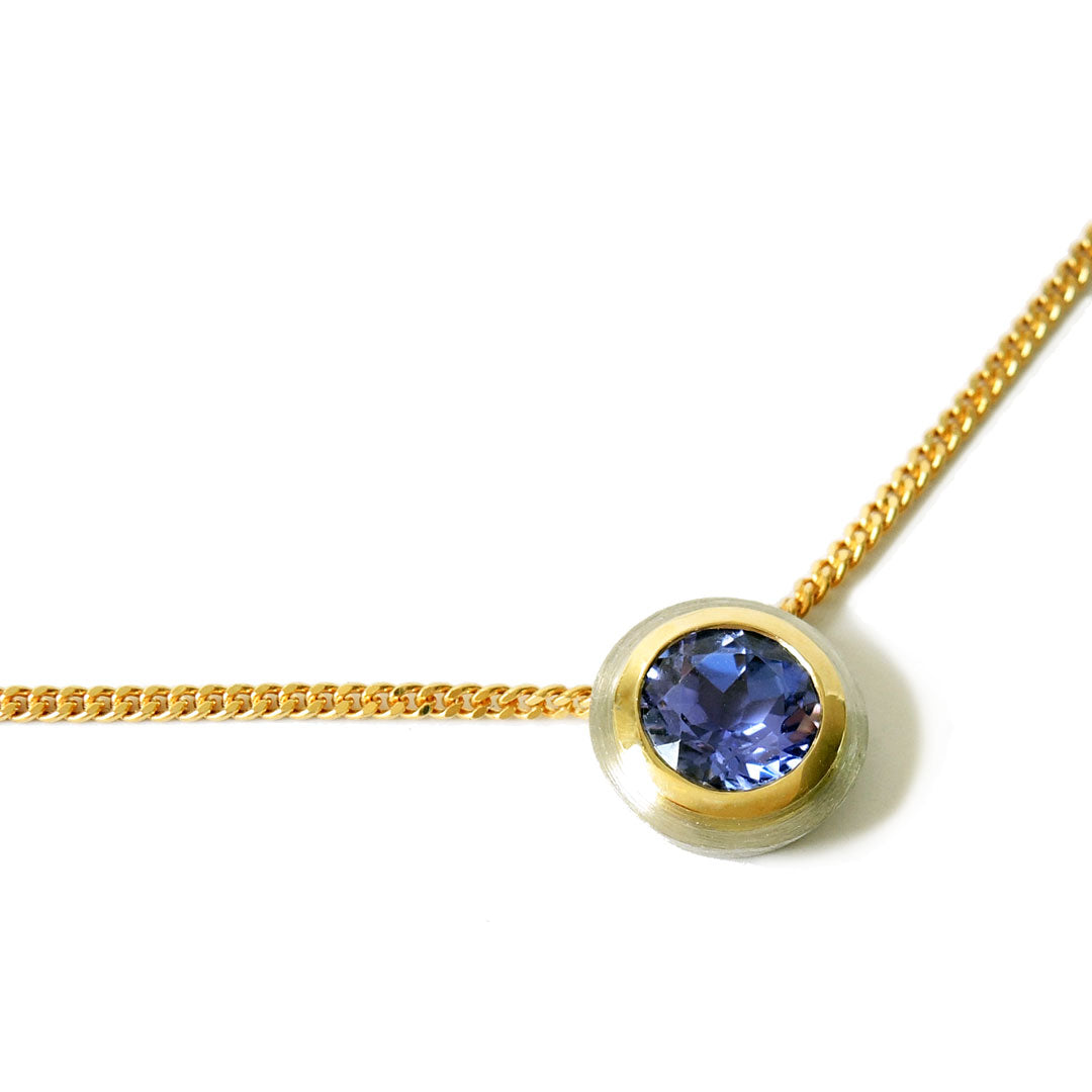 Tanzanite, bezel set in platinum and 18k on a fine 18k chain with a lobster clasp, on a white background. 
