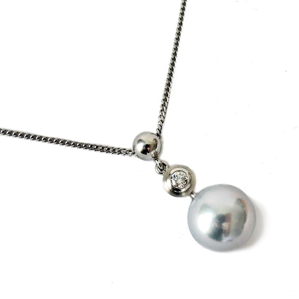 Platinum pendant with an .05 ct. bezel set diamond and a 9 mm pale blue Akoya pearl on a prop neck. 