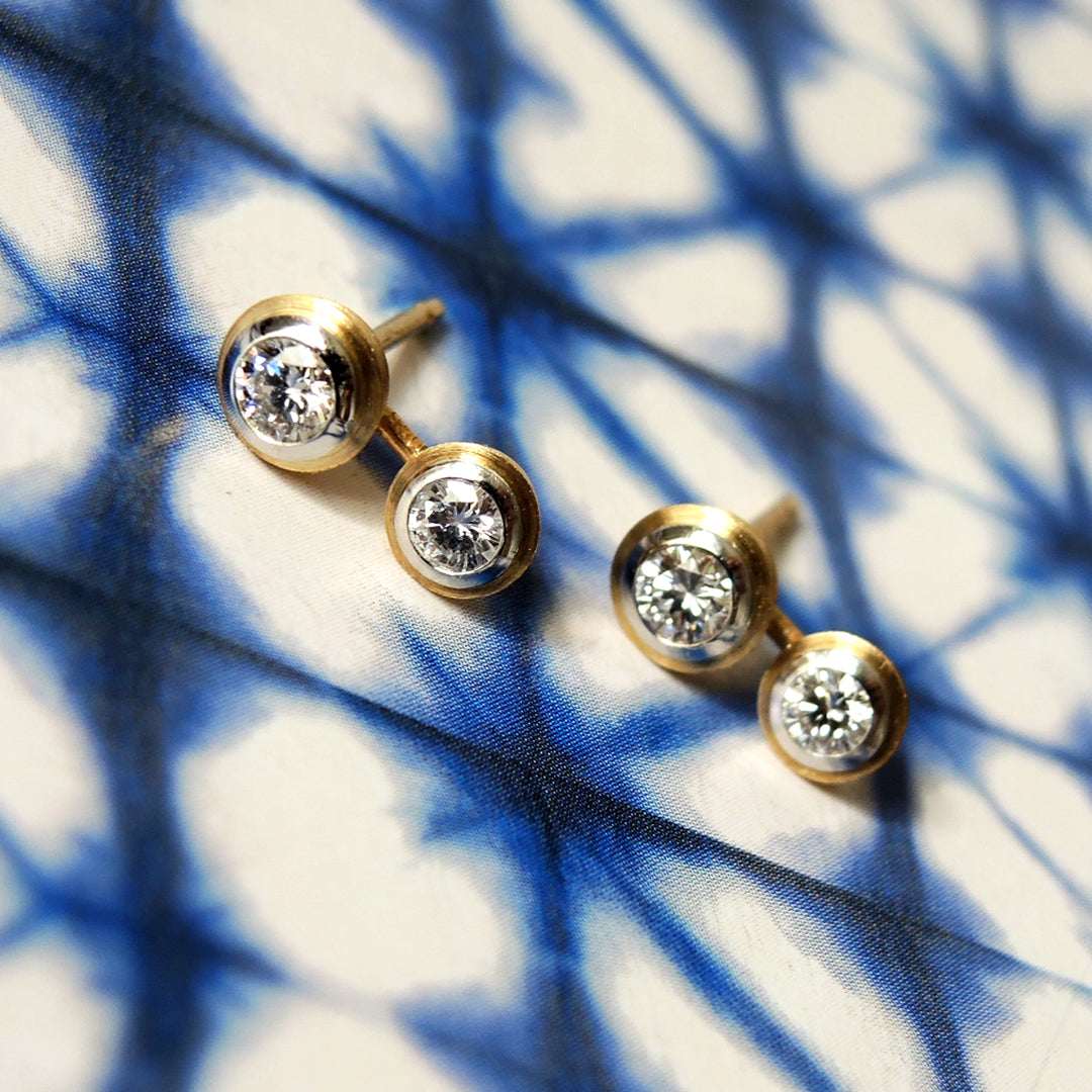 Bezel set gold and platinum studs witth diamonds on a shibori patterned paper