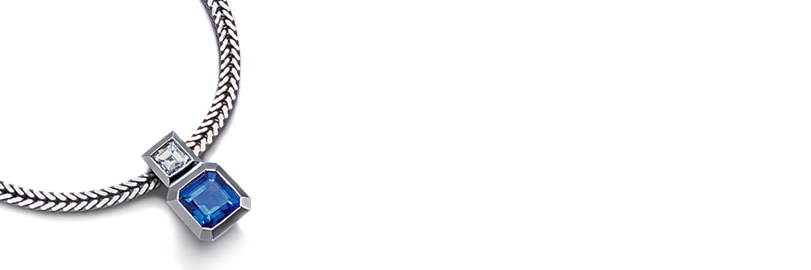 Necklace with an emerald cut square blue sapphire and step cut diamond in platinum on a white background