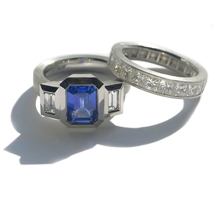 Bezel Set 3 stone ring in platinum with a large blue sapphire and diamonds with a channel set diamond band. 