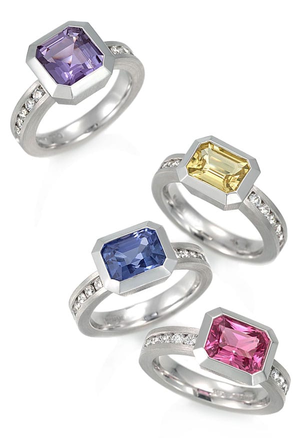 4 bezel set colored stone rings in platinum with channel set diamonds in the bands. 
